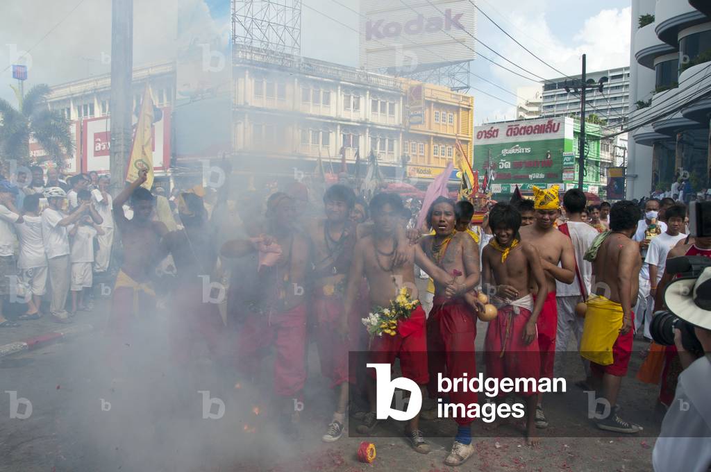Thailand: Firecrackers explode over shrine bearers and they are quickly enveloped in thick smoke, street procession, Phuket Vegetarian Festival