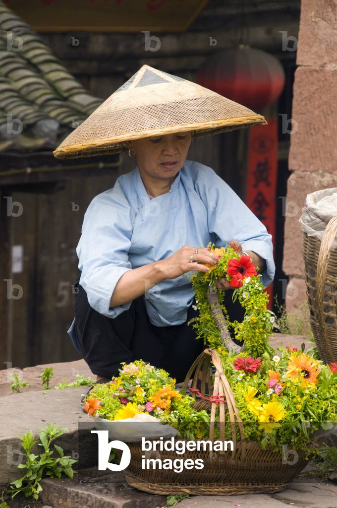 China: Tujia woman selling flower tiaras at the North Gate Tower, Fenghuang, Hunan Province