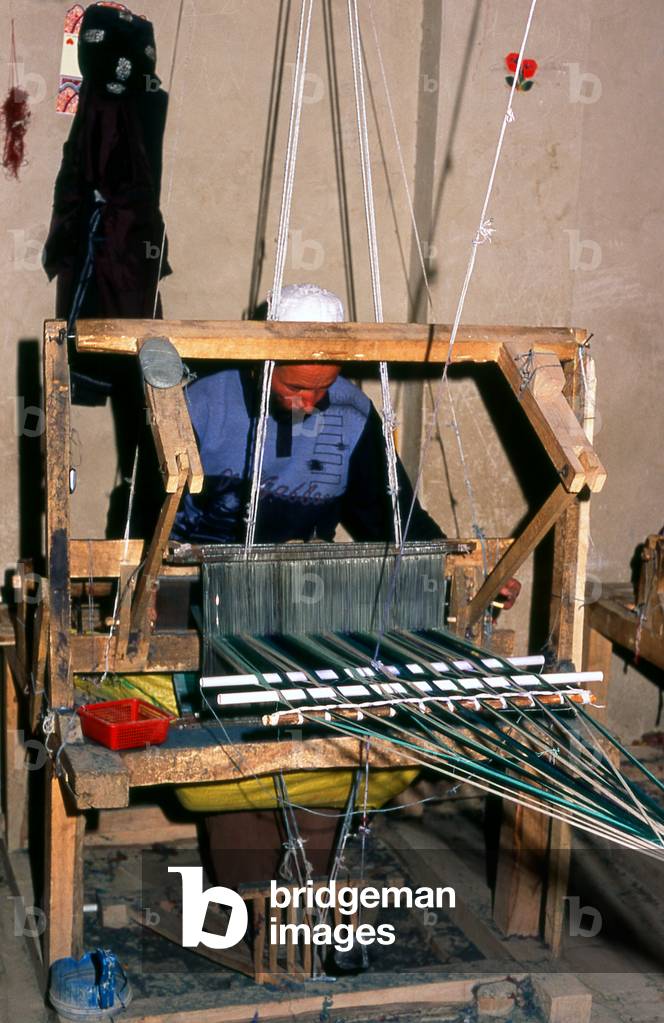 China: A Uighur man silk weaving, Atlas Silk Workshop (Atlas Karakhana) in Jiya Village, about 13km northeast of Khotan, Xinjiang Province