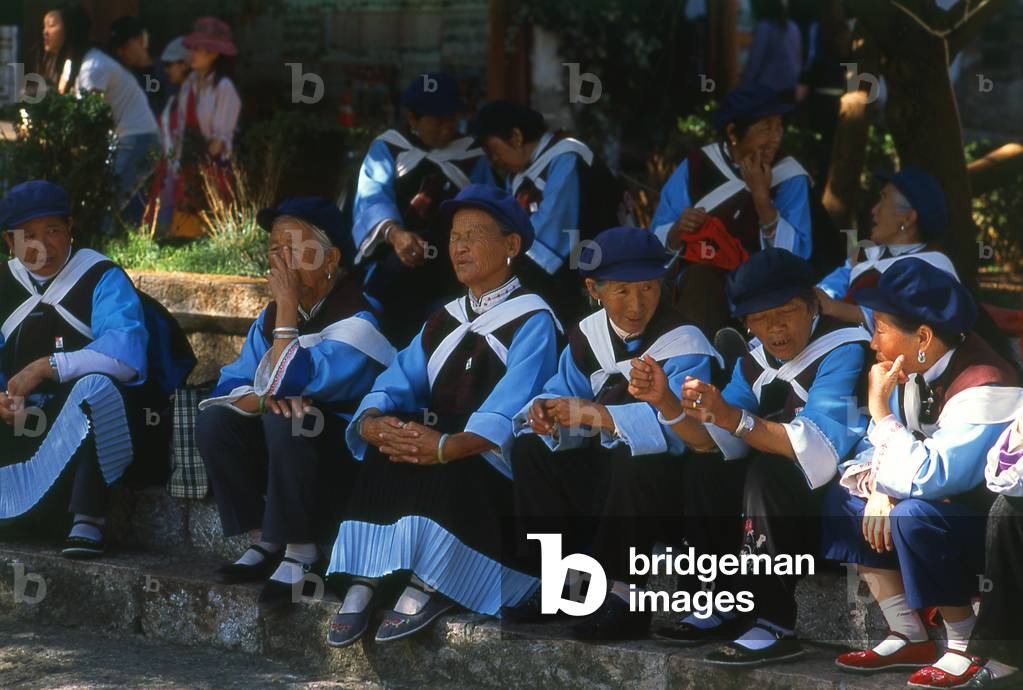 China: Naxi women relax in the Old Market Square (Sifang Jie), Old Town, Lijiang, Yunnan Province