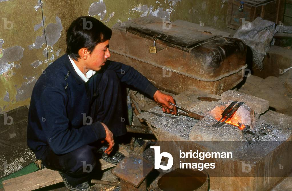 China: Crafting a highly decorative traditional hand-made knife in a small workshop in Yengisar, Xinjiang Province (photo)