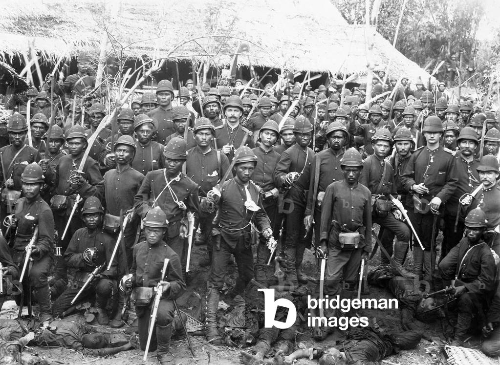Indonesia / Netherlands: Korps Marechaussee soldiers in Dutch service stand over the bodies of defeated Acehnese at Pedir, Aceh, Sumatra in 1898. Aceh War (1873 - 1914)