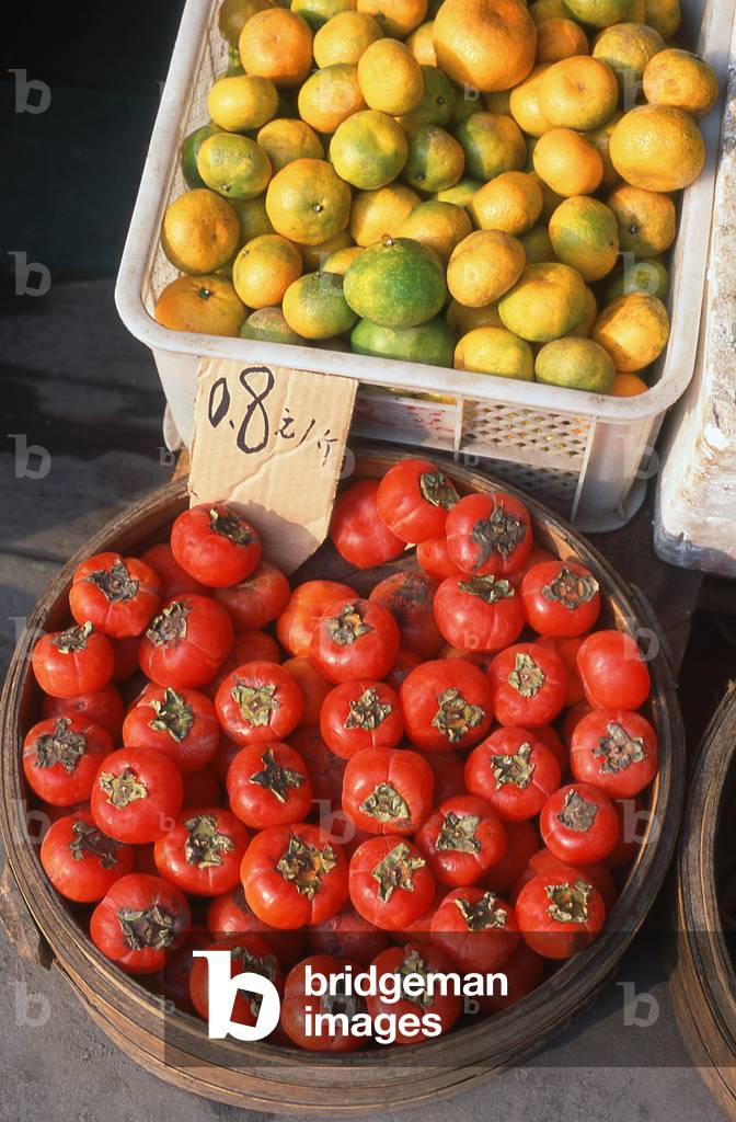 China: Red persimmons and oranges for sale in a market in Kunming, Yunnan Province (photo)