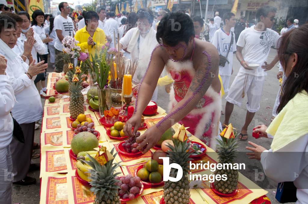 Thailand: Entranced devotee or 'Ma Song' visits a street altar set up by a shop owner looking for blessings from passing devotees, Phuket Town, Phuket Vegetarian Festival