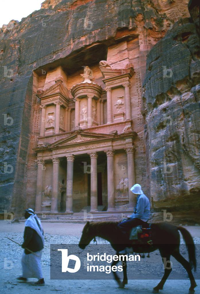 Jordan: A man leads a tourist on horseback  in front of Al Khazneh (The Treasury), Petra