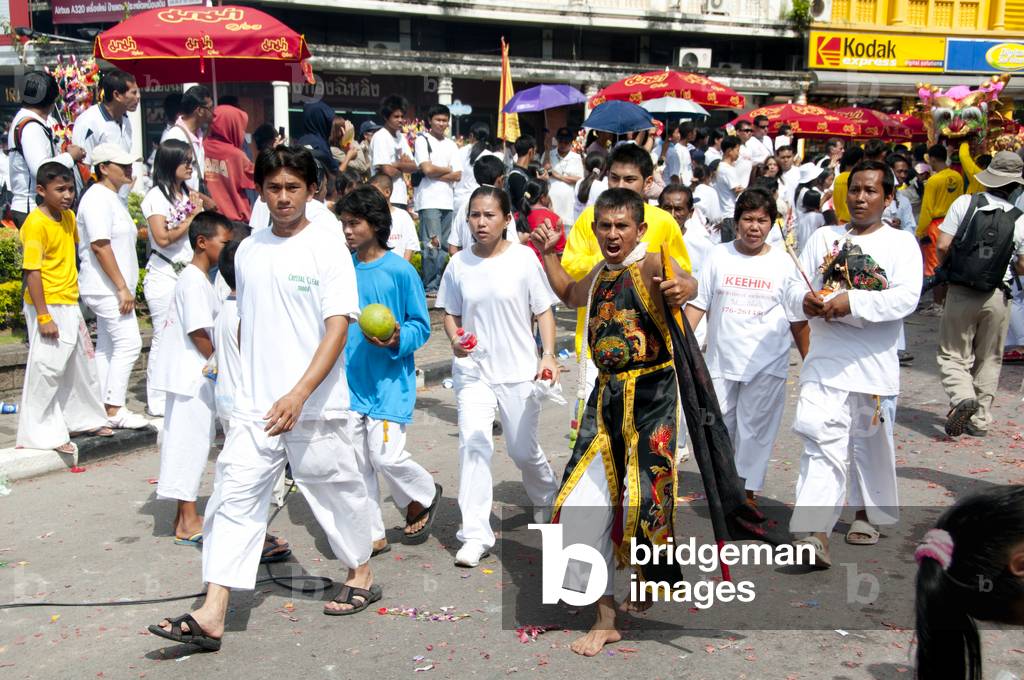 Thailand: Entranced devotee or 'Ma Song' with his attendants in a procession through Phuket Town, Phuket Vegetarian Festival