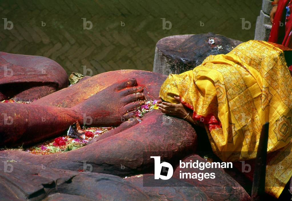 Nepal: A woman worshipping at the reclining Vishnu statue in the Hindu Budhanilkantha Temple, Budhanilkantha, Kathmandu Valley