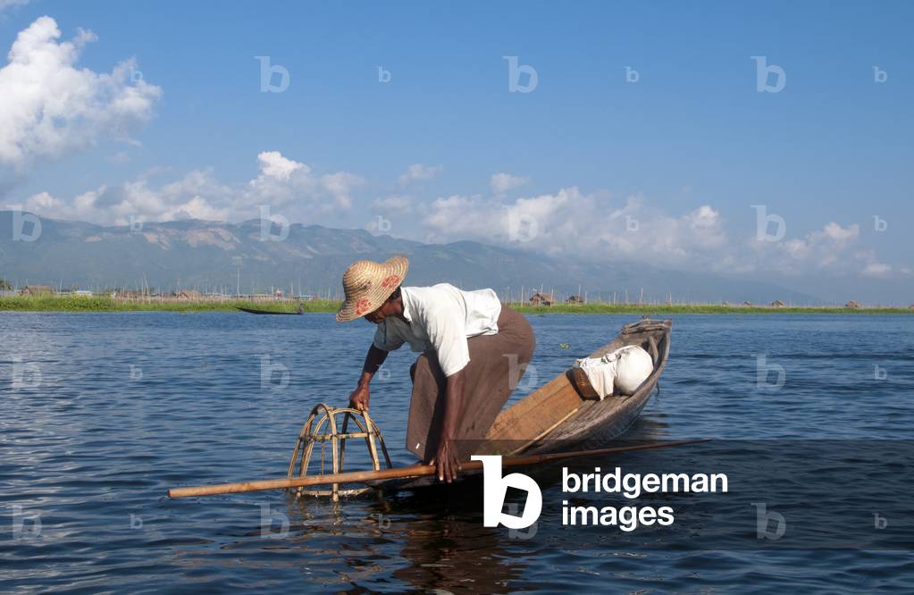 Burma / Myanmar: A leg rowing Intha fisherman shows off his skills with a large conical fish trap at Inle Lake, Shan State