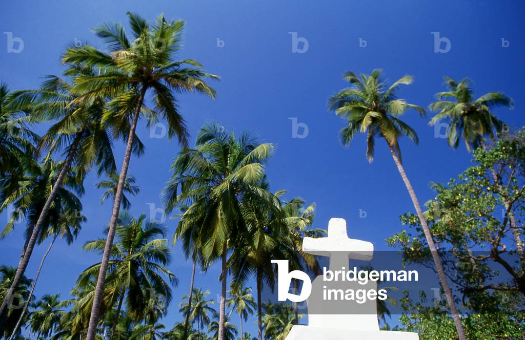 India: A Christian crucifix in front of coconut palms on a Goan beach, Goa