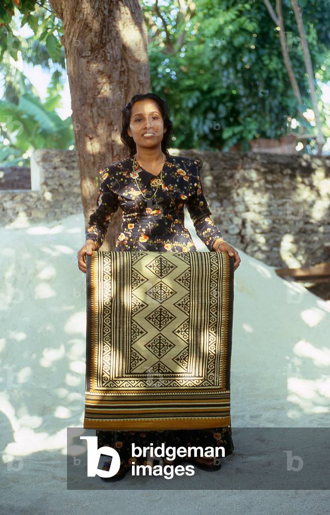 Maldives: A weaver with one of her finished grass 
