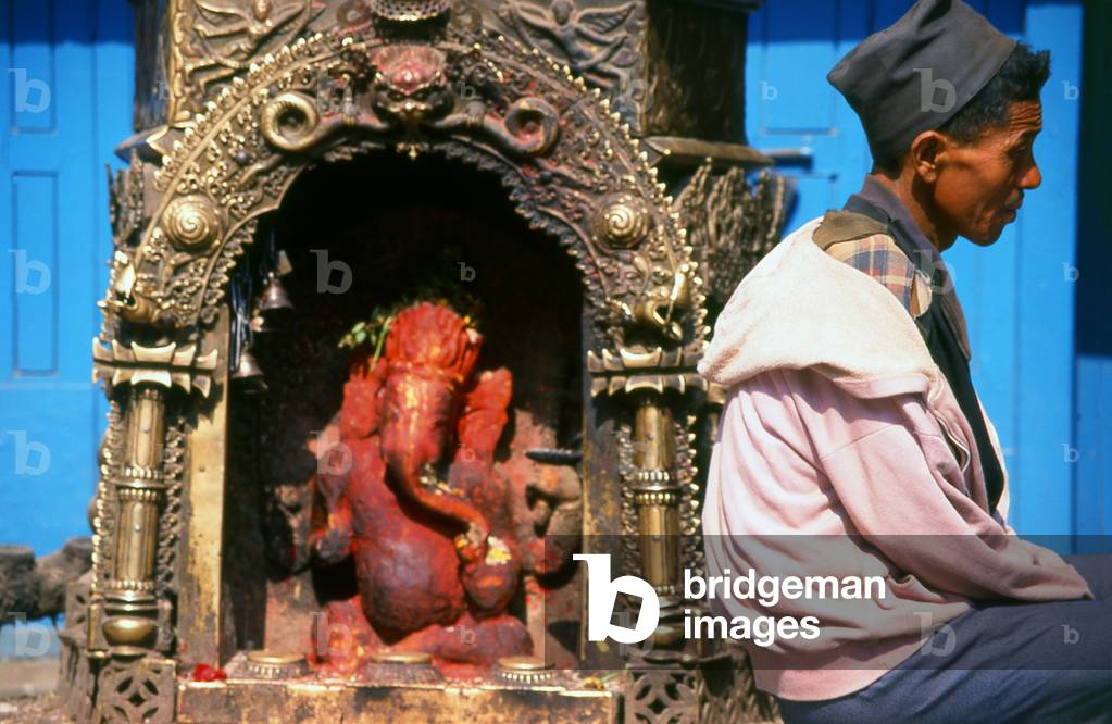 Nepal: A man sits in contemplation in front of a shrine to the elephant-headed Hindu god Ganesh, Kathmandu