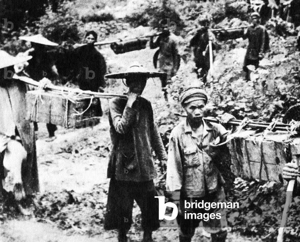 Laos: Lao and Vietnamese porters carrying supplies south along the Hoi Chi Minh Trail to resupply the insurgency in the south, c. 1963.