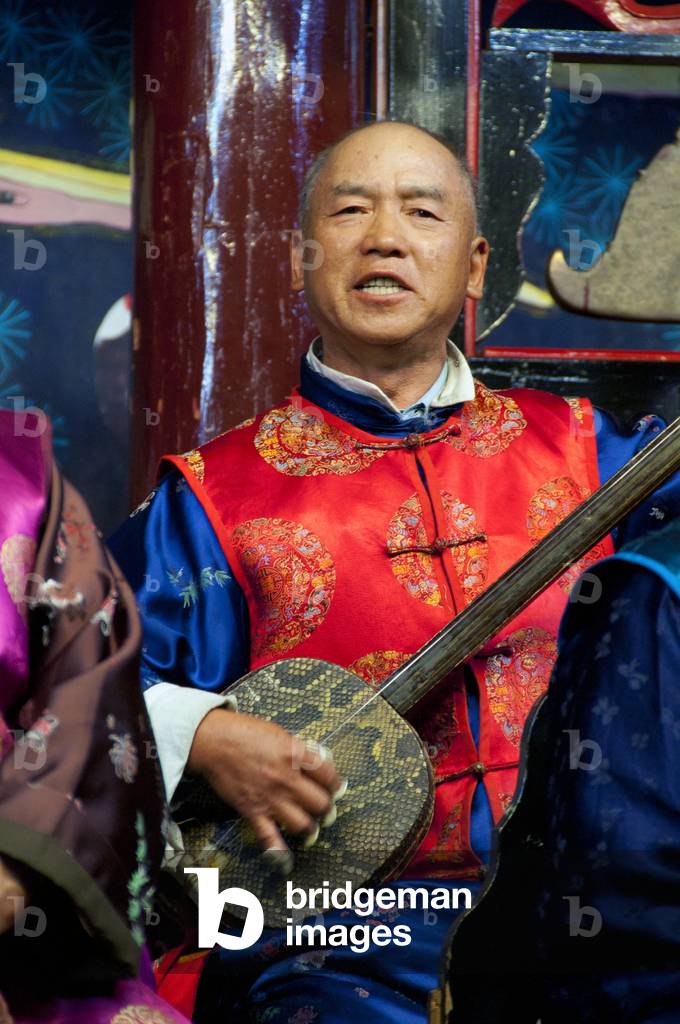 China: A man plays a sanxian, the Naxi (Nakhi) Folk Orchestra, Naxi Orchestra Hall, Lijiang Old Town, Yunnan Province