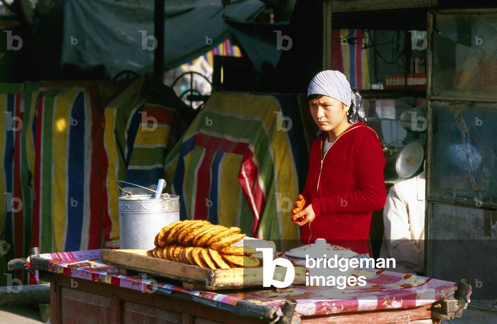 China: Young Uighur woman selling breads for breakfast, Yarkand, Xinjiang Province