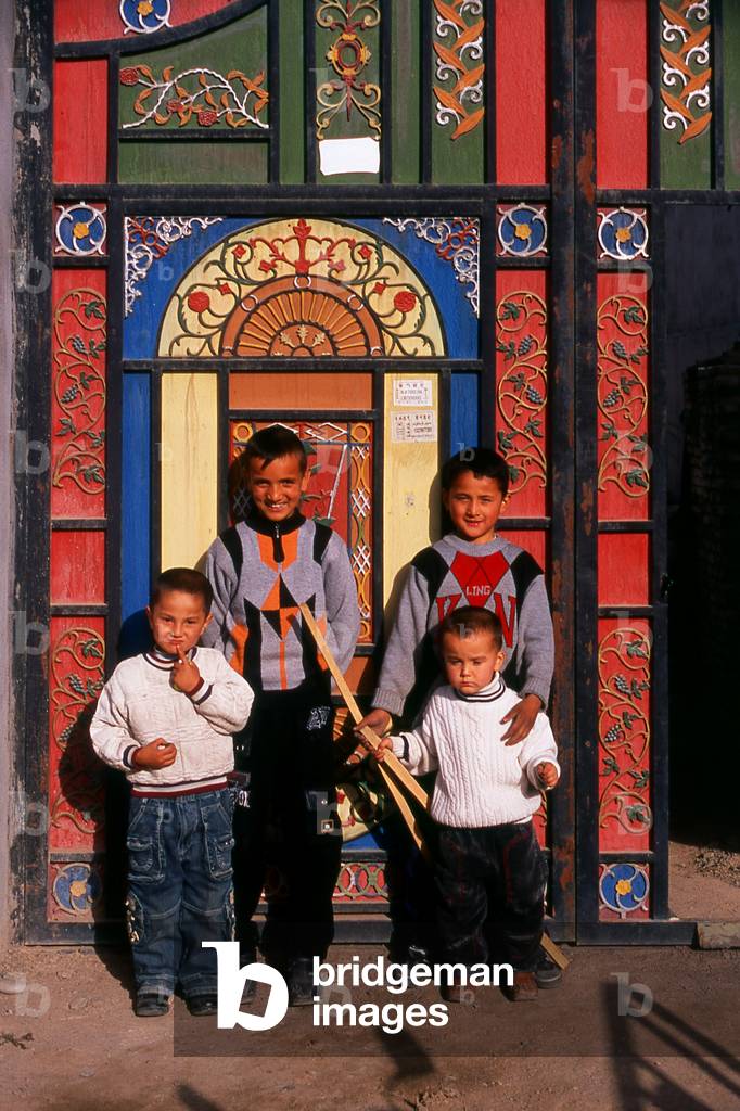 China: Young boys in front of their home's brightly decorated doors in Old Kuqa, Xinjiang Province