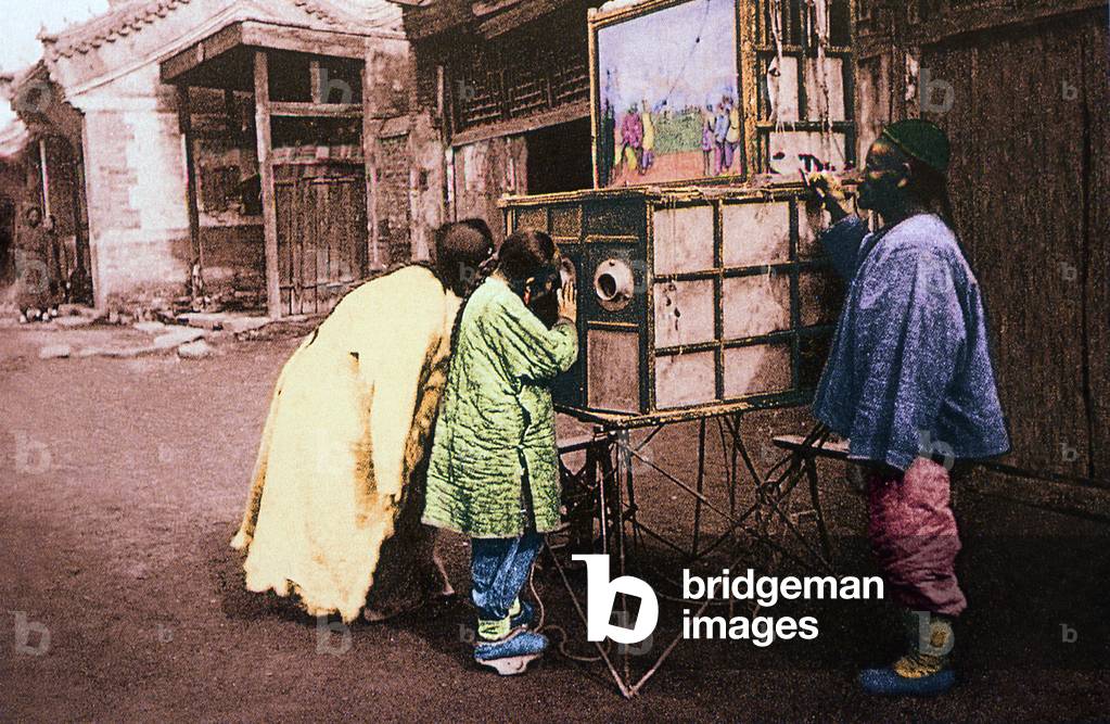 China:  Children looking at a mobile peepshow, Beijing, late Qing Dynasty (c.1900)