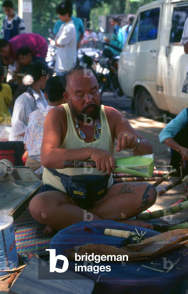 Thailand: A beetle fighting aficionado complete with lucky amulets on the banks of the Ping River, Chiang Mai, northern Thailand