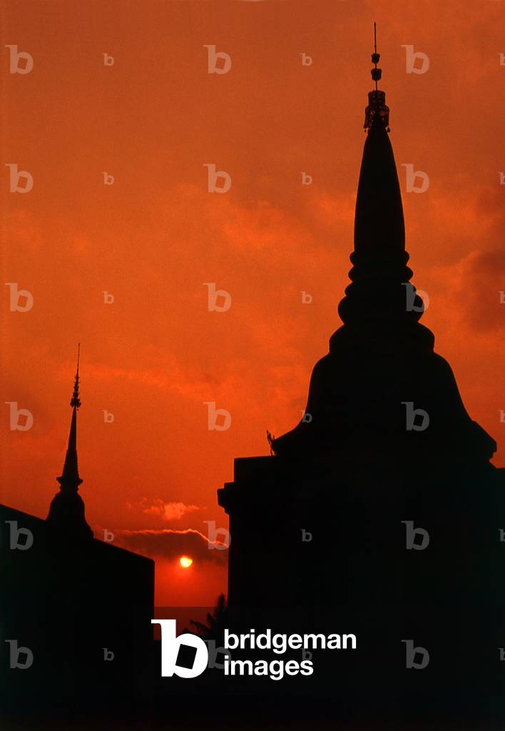 Thailand: The sun sets over the spires of a Chiang Mai temple, northern Thailand