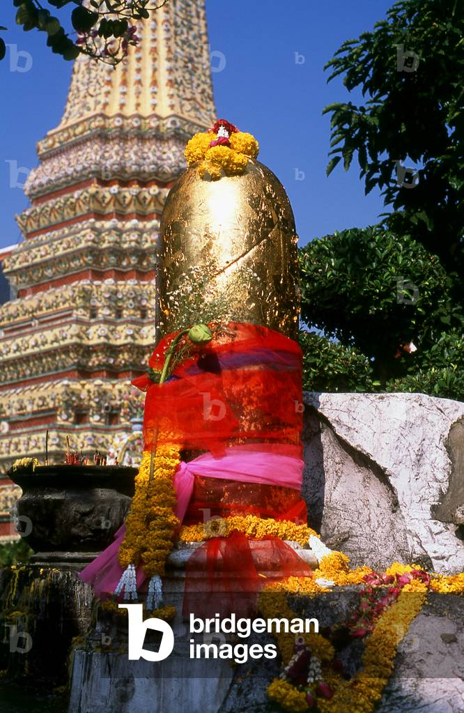 Thailand: Gold leaf enshrouded phallus statue with flower garlands in the grounds of Wat Pho (Temple of the Reclining Buddha), Bangkok
