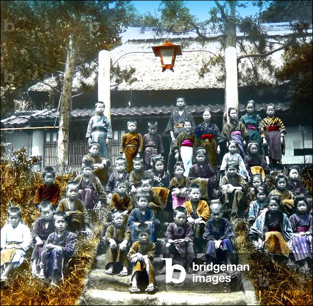 Japan: A large group of schoolchildren posing on steps in the school grounds, c.1900