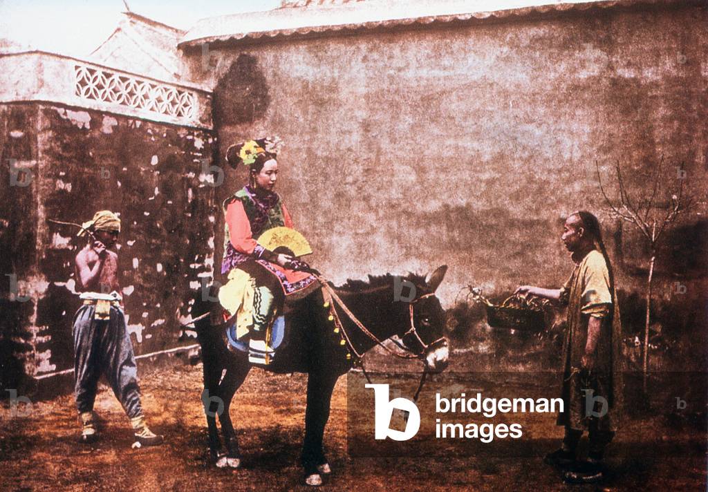 China: A woman in her Qing finery rides a donkey, Late Qing Dynasty photograph (1887)