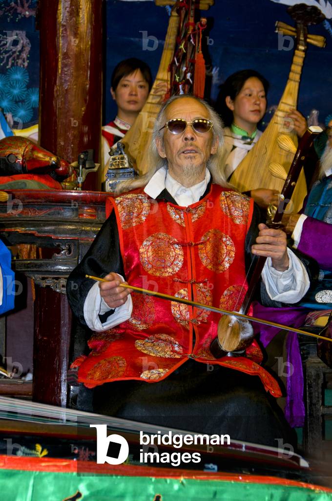 China: A man plays a banhu, the Naxi (Nakhi) Folk Orchestra, Naxi Orchestra Hall, Lijiang Old Town, Yunnan Province
