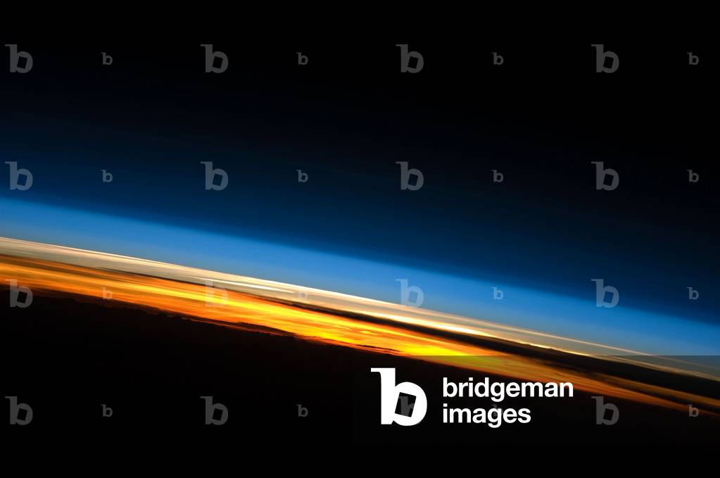 Earth's atmosphere and setting sun - Earth's atmosphere and setting sun - Earth's atmosphere seen at sunset from the International Space Station (ISS) on May 25, 2010. This spectacular image of sunset on the Indian Ocean was taken by astronauts aboard the International Space Station (ISS). The image presents an edge - on, or limb view, of the Earth's atmosphere as seen from orbit. The Earth's curvature is visible along the horizon line, or limb, that extends across the image from center left to lower right. Above the darkened surface of the Earth, a brilliant sequence of colors roughly denotes several layers of the atmosphere. Deep oranges and yellows appear in the troposphere, which extends from the Earth's surface to 6 - 20 km high. This layer contains over 80 percent of the mass of the atmosphere and almost all of the water vapor, clouds, and precipitation. Several dark cloud layers are visible within this layer. Variations in the colors are due mainly to varying concentrations of either clouds or aerosols (airborne particles or droplets). The pink to white region above the clouds appears to be the stratosphere; this atmospheric layer generally has little or no clouds and extends up to approximately 50 km above the Earth's surface. Above the stratosphere, blue layers mark the upper atmosphere (including the mesosphere, thermosphere, ionosphere, and exosphere) as it gradually fades into the blackness of outer space. The ISS was located over the southern Indian Ocean when this picture was taken, with the astronaut observer looking towards the west. Astronauts aboard the ISS see 16 sunrises and sunsets per day due to their high orbital velocity (greater than 28,000 km per hour). The multiple chances for photography are fortunate, as at that speed each sunrise or sunset event only lasts a few seconds. This astronaut photograph was acquired on May 25, 2010