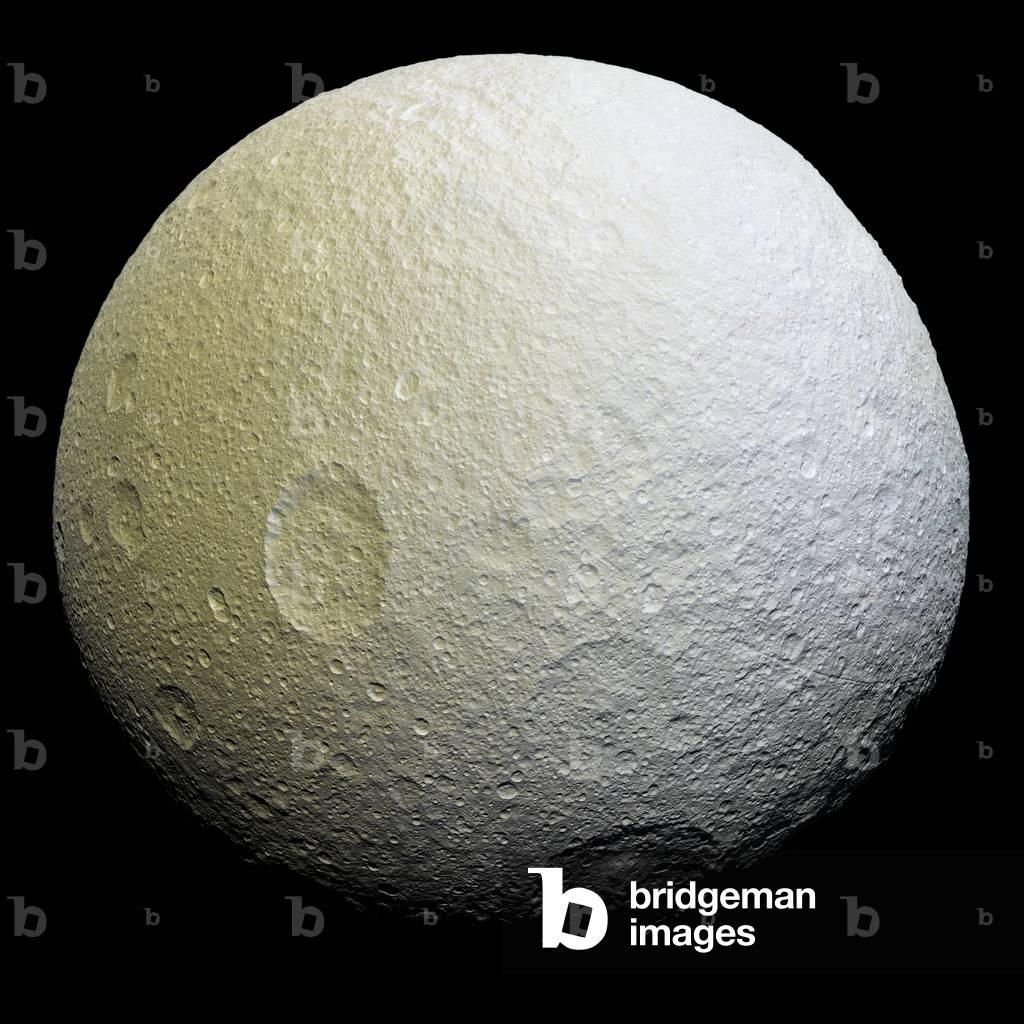 Tethys, Saturn satellite, seen by the Cassini probe - Saturn's moon Tethys seen by Cassini spacecraft: The Tethys satellite photographed by the Cassini probe on 11 April 2015 has a distance of 53,000 km from the satellite. Tethys is about 1070 km in diameter. - This enhancement-color mosaic of Saturn's icy moon Tethys shows a range of features on the moon's trailing hemisphere. Tethys is tidally locked to Saturn, so the trailing hemisphere is the side of the moon that always faces opposite its direction of motion as it orbits the planet - Images taken using clear, green, infrared and ultraviolet spectral filters were combined to create the view, which highlights subtle color differences across Tethys' surface at wavelengths not visible to human eyes. The moon's surface is fairly uniform in natural color - The color of the surface changes conspicuously across the disk, from yellowish hues to nearly white. These broad color changes are affected by a number of external processes. First, Saturn's diffuse E-ring preferentially bombards Tethys' leading hemisphere, towards the right side of this image, with ice bright ice grains. At the same time, charged particles from Saturn's radiation belt bombard the surface on the trailing side, causing color changes due to chemical alteration of the materials there. The albedo - a measure of the surface's reflectivity - drops by 10 to 15 percent from the moon's leading side to the trailing side. Similar global color patterns exist on other Saturnian moons - This mosaic is an orthographic projection constructed from 52 Cassini images obtained on April 11, 2015 with the Cassini spacecraft narrow-angle camera. Resolution is about 1,000 feet (300 meters) per pixel. The images were obtained at a distance of approximately 33,000 miles (53,000 kilometers) from Tethys