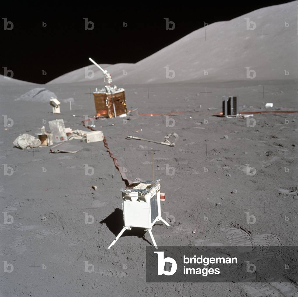 Apollo 17: experience LEAM - The Lunar Ejecta and Meteorite (LEAM) experiment - Apollo 17 - LEAM (white box in the foreground) is the acronym for Lunar Ejecta And Meteorites; this instrument was installed by astronauts of the Apollo 17 mission to study dust ejected by meteorite impacts on the surface of the Moon. The Lunar Ejecta and Meteorite (LEAM) instrument as deployed at the Apollo 17 ALSEP site. The central station is directly behind it, the RTG to the right of that, and the Lunar Surface Gravimeter (LSG) to the left of the central station. Discarded pallets and trash are also visible. The North Massif dominates the right side of the picture. The objectives of the LEAM experiment were to detect secondary particles that had been ejected by meteorite impacts on the lunar surface and to detect primary micrometeorites themselves. The 3 classes of particles encountered by the LEAM included lunar ejecta, interstellar grains, and cometary debris, all of which can be considered under the title of cosmic dust. The experiment measures particle speed, radiant direction, particle momentum, and particle kinetic energy. The particle detectors of the instrument were multi - layered arrays that were capable of measuring the velocity and energy of incident particles. It consisted of 3 sensors - East, West, and Up. It stood on 4 legs and was connected to the ALSEP central station by a cable. 11 Dec 1972