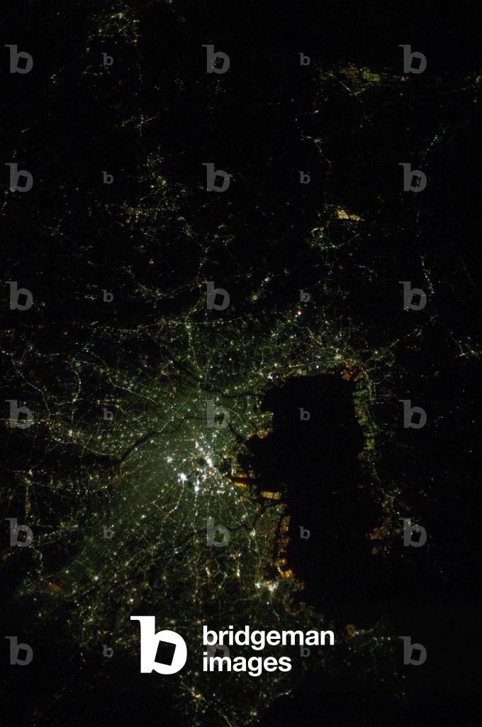 Tokyo night view - Tokyo at Night - Tokyo night view from the International Space Station (ISS) on February 5, 2008. The green blue colour of urban lighting is due to the use of mercury vapour lamps. This nighttime photograph of Tokyo, Japan, was taken by an International Space Station astronaut on February 5, 2008. The heart of the city is brightest, with ribbons of lights radiating outward from the center along streets and railways. The regularly spaced bright spots along one of the ribbons heading almost due west out of the downtown area are probably train stations along a public transit route. The lights of Tokyo are a cooler blue - green color than many other world cities. The color results from the more widespread use of mercury vapor lighting as opposed to sodium vapor lighting, which produces an orange - yellow light