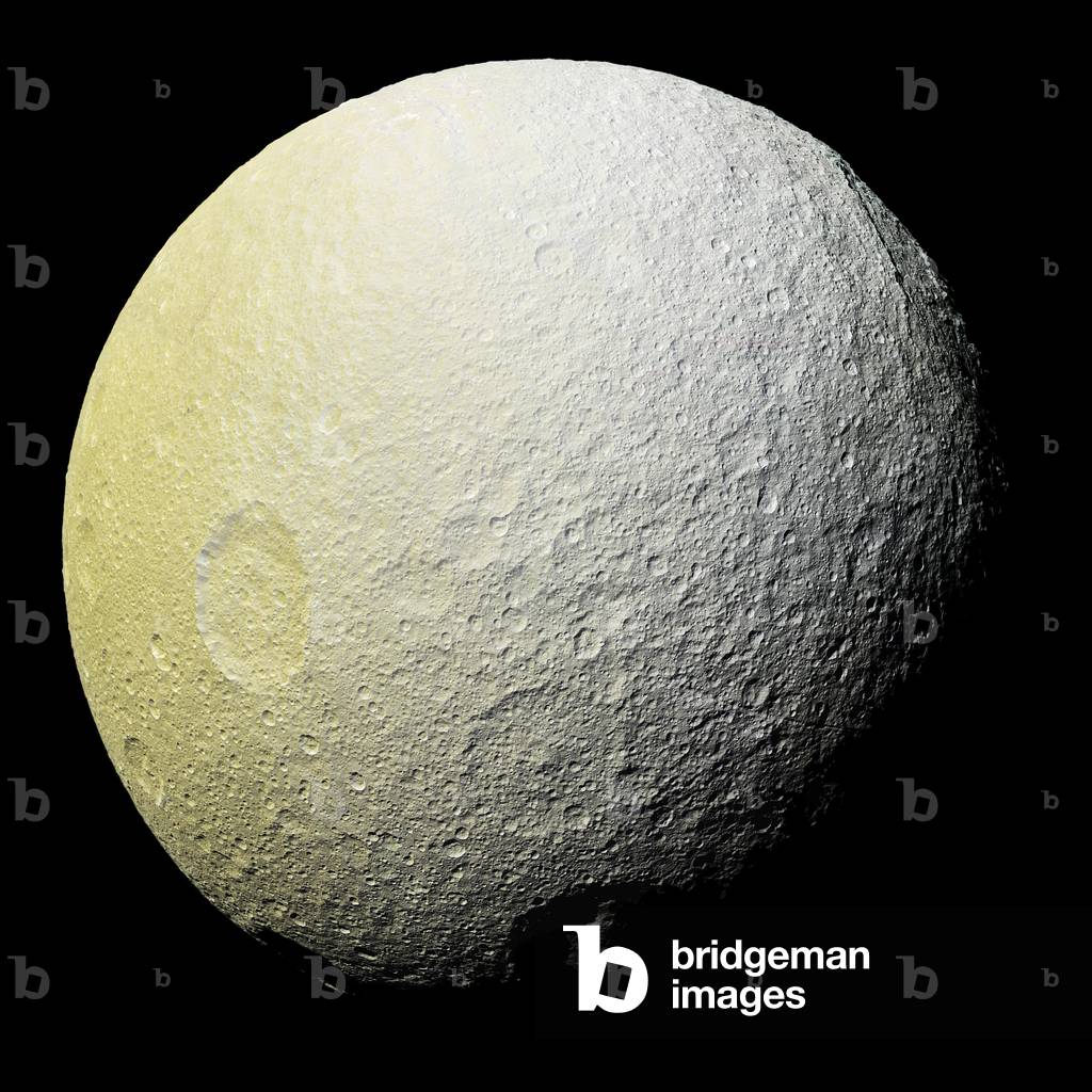 Tethys, Saturn satellite, seen by the Cassini probe - Saturn's moon Tethys seen by Cassini spacecraft: The Tethys satellite photographed by the Cassini probe on 11 April 2015 has a distance of 53,000 km from the satellite. Tethys is about 1070 km in diameter. - This enhancement-color mosaic of Saturn's icy moon Tethys shows a range of features on the moon's trailing hemisphere. Tethys is tidally locked to Saturn, so the trailing hemisphere is the side of the moon that always faces opposite its direction of motion as it orbits the planet - Images taken using clear, green, infrared and ultraviolet spectral filters were combined to create the view, which highlights subtle color differences across Tethys' surface at wavelengths not visible to human eyes. The moon's surface is fairly uniform in natural color - The color of the surface changes conspicuously across the disk, from yellowish hues to nearly white. These broad color changes are affected by a number of external processes. First, Saturn's diffuse E-ring preferentially bombards Tethys' leading hemisphere, towards the right side of this image, with ice bright ice grains. At the same time, charged particles from Saturn's radiation belt bombard the surface on the trailing side, causing color changes due to chemical alteration of the materials there. The albedo - a measure of the surface's reflectivity - drops by 10 to 15 percent from the moon's leading side to the trailing side. Similar global color patterns exist on other Saturnian moons - Mountains on the floor of the 280 mile- (450 km-) wide Odysseus impact basin are visible at upper right, around the two o'clock position - This mosaic is an orthographic projection constructed from 52 Cassini images obtained on April 11, 2015 with the Cassini spacecraft narrow-angle camera. Resolution is about 1,000 feet (300 meters) per pixel. The images were obtained at a distance of approximately 33,000 miles (53,000 kilometers) from Tethys