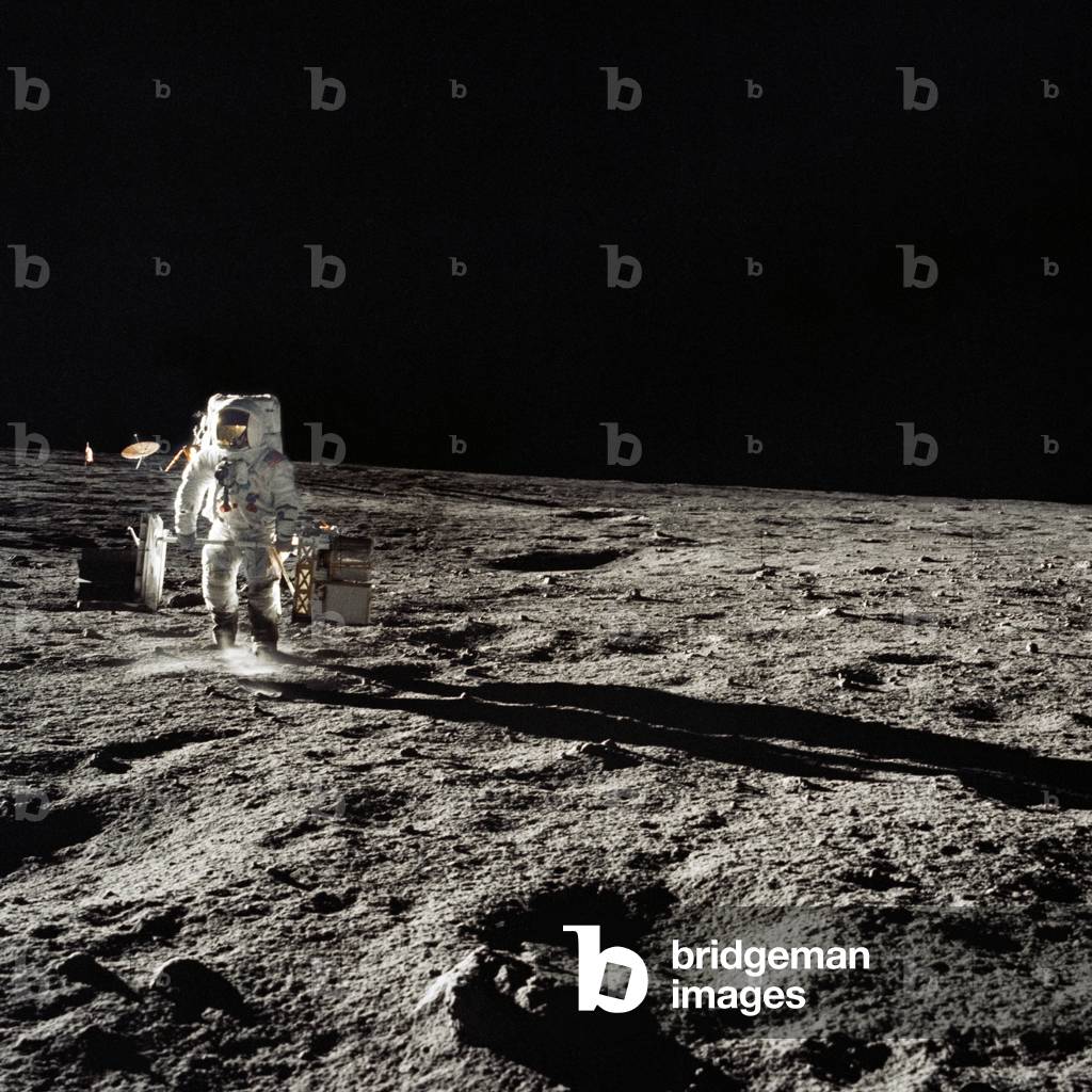 Apollo 12: A. Bean on the Moon - Apollo 12: A. Bean on the Moon - Alan L. Bean carries scientific instruments to be deployed on the Moon. 19/11/1969. Astronaut Alan L. Bean, lunar module pilot, traverses with the two sub packages of the Apollo Lunar Surface Experiments Package (ALSEP) during the first Apollo 12 extravehicular activity (EVA). Bean deployed the ALSEP components 300 feet from the Lunar Module (LM). The LM and deployed erectable S - band antenna can be seen in the background. 19 Nov 1969