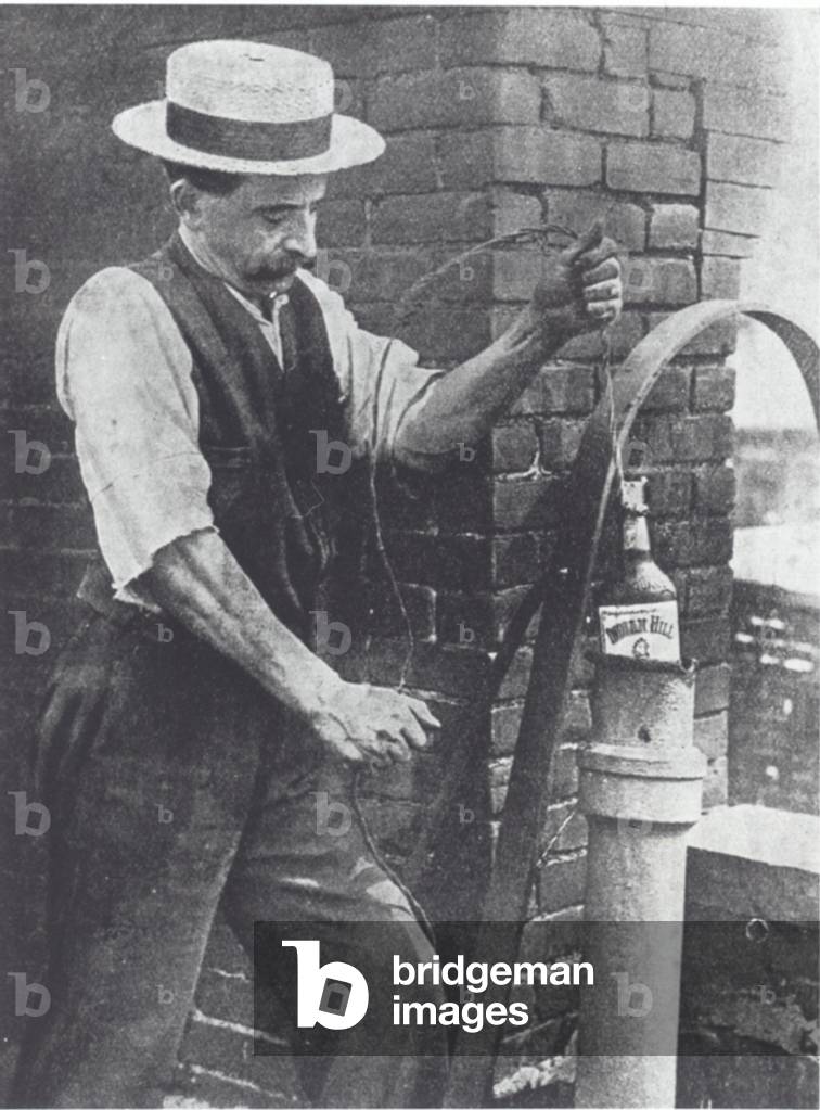 Man hiding an illegal bottle of whisky in a pipe (b/w photo)