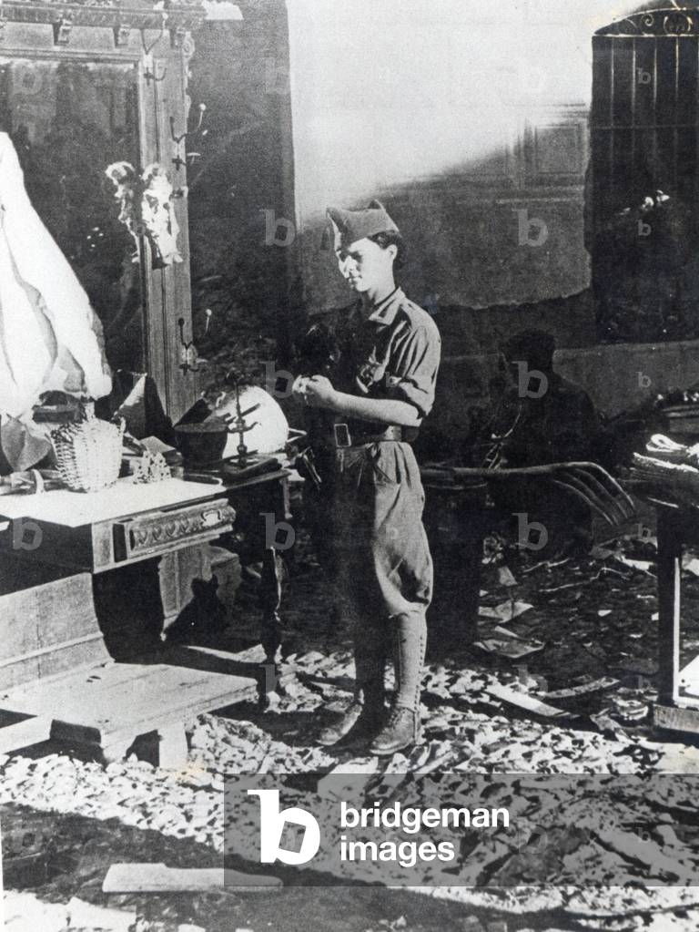 A female soldier of the Nationalist forces stands in the ruins of a house, 1936-39 (b/w photo)