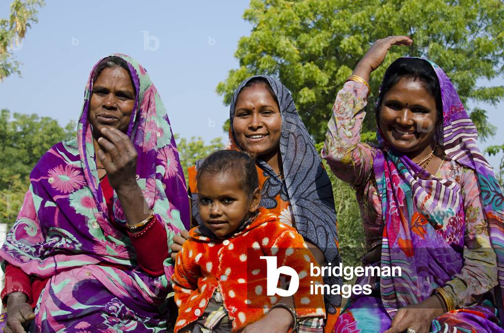 Three smiling Rajasthani women and girl in colourful dresses,
Gagadi (aka. Gagari) village, Rajasthan, India (photo)