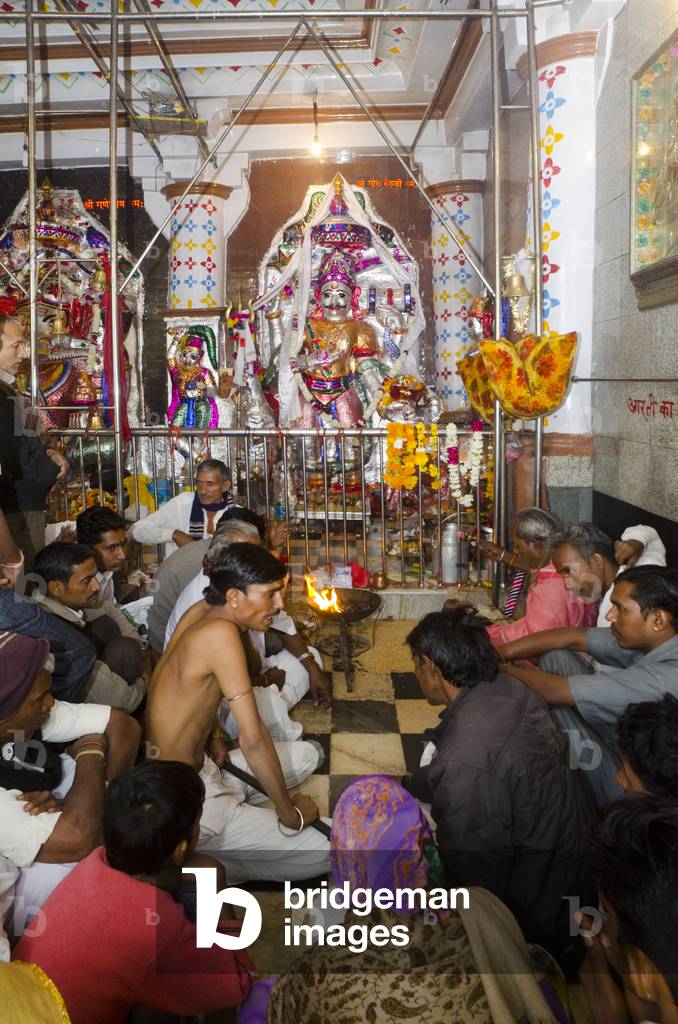 Hindu priest talking to devotees making offerings in Ganesh temple, Mandore Gardens, Jodhpur, Rajasthan, India (photo)