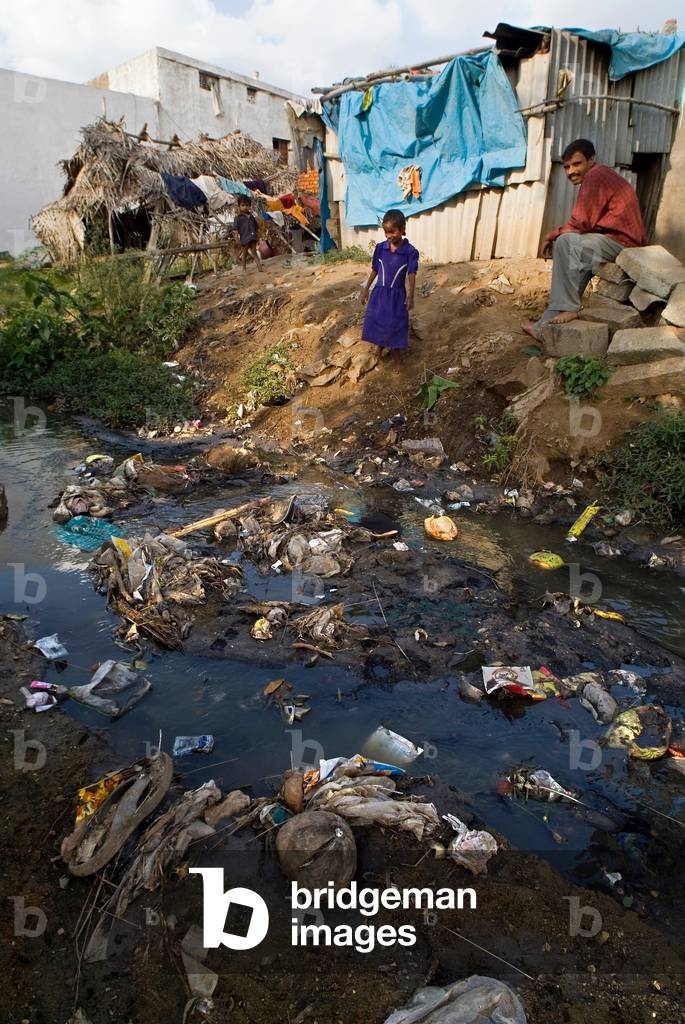 Slum residents on the edge of a polluted stream in Rajagopal Nagar, Bangalore, Karnataka, India
