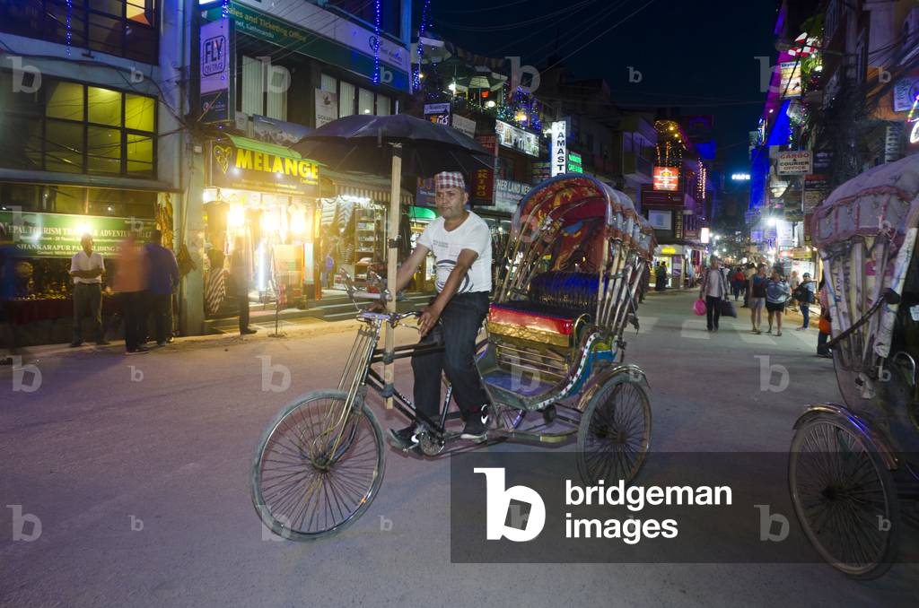 Cycle rickshaw driver on Thamel street at night, 
Thamel, Kathmandu, Nepal (photo)