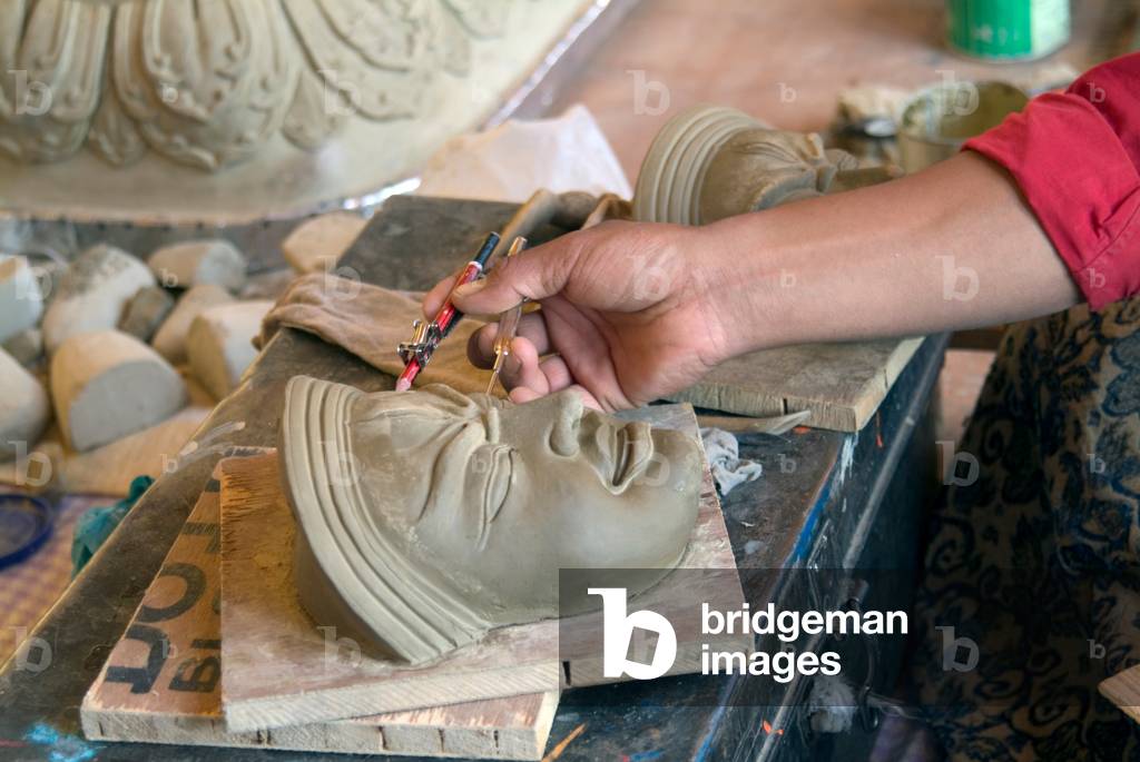 Artist in Tibetan Buddhist monastery sculpting new clay masks for temple display (here: measuring traditionally prescribed proportions) Thiksey (aka. Tikse) gompa, Ladakh, Himalayas, Jammu and Kashmir, India (photo)