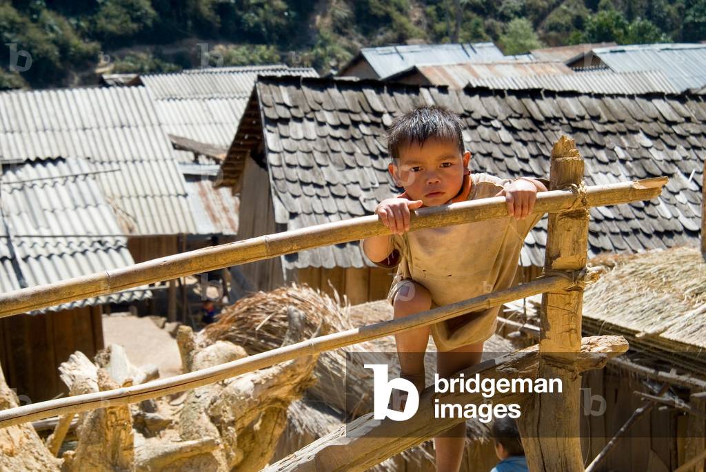 Young boy/toddler climbing fence in remote tropical forest village,
nr. Korsan Tai, Phienghong, Nonghet District, Xieng Khouang Province, Laos, Indochina, Southeast Asia