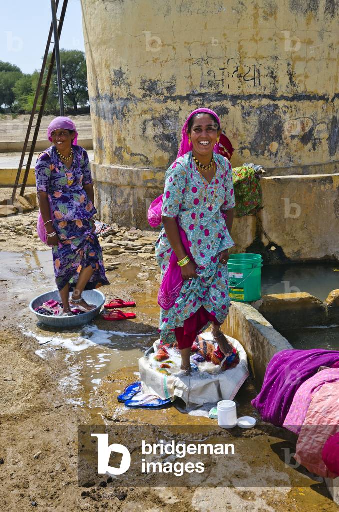 Women washing clothes with their feet at a village watering trough in Tejwa, Thar Desert, Rajasthan, India (photo)