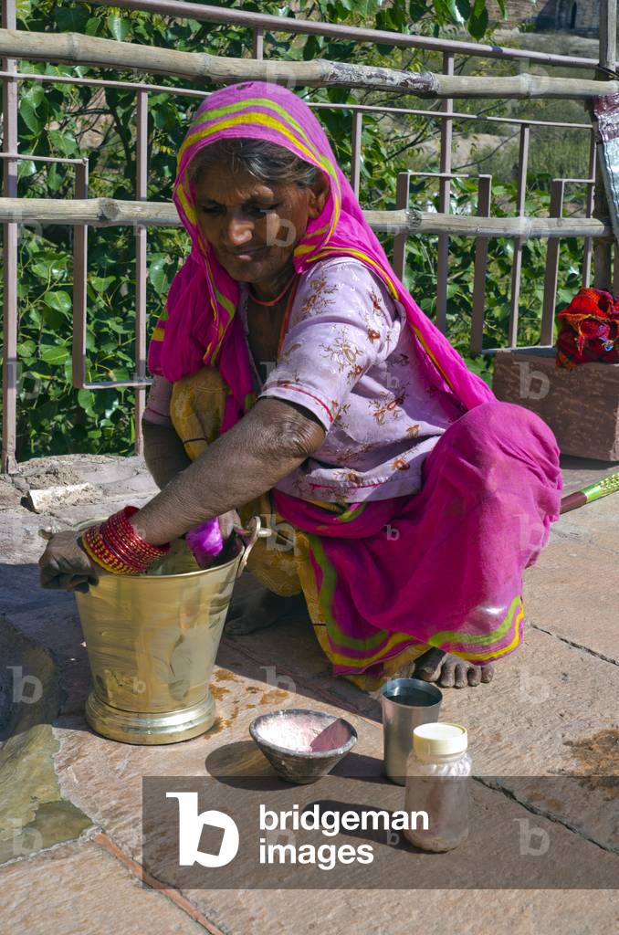 Elderly Indian woman cleaning temple brass bucket,
Chamunda Mataji temple, Mehrangarh Fort,
Jodhpur, Rajasthan, India (photo)