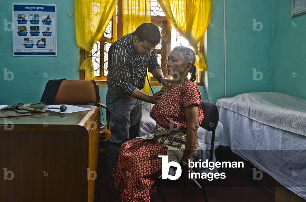 Doctor examining elderly woman patient in village health clinic implemented by Kahare, Chalnakhel, Kathmandu Valley, Nepal (photo)