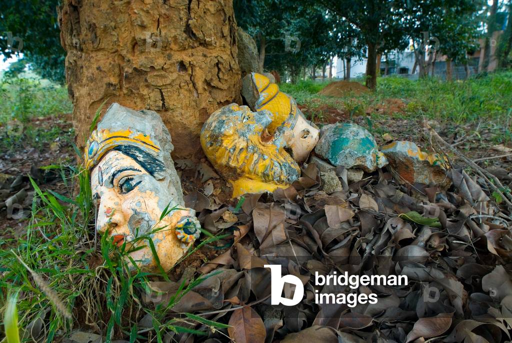 Broken Hindu statue heads at base of a tree in the backyard of the Durga Devi temple (photo)