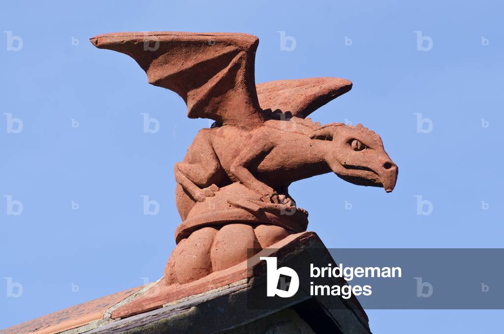 Winged dragon gargoyle ornament on apex of house roof, Gower, South Wales (photo)