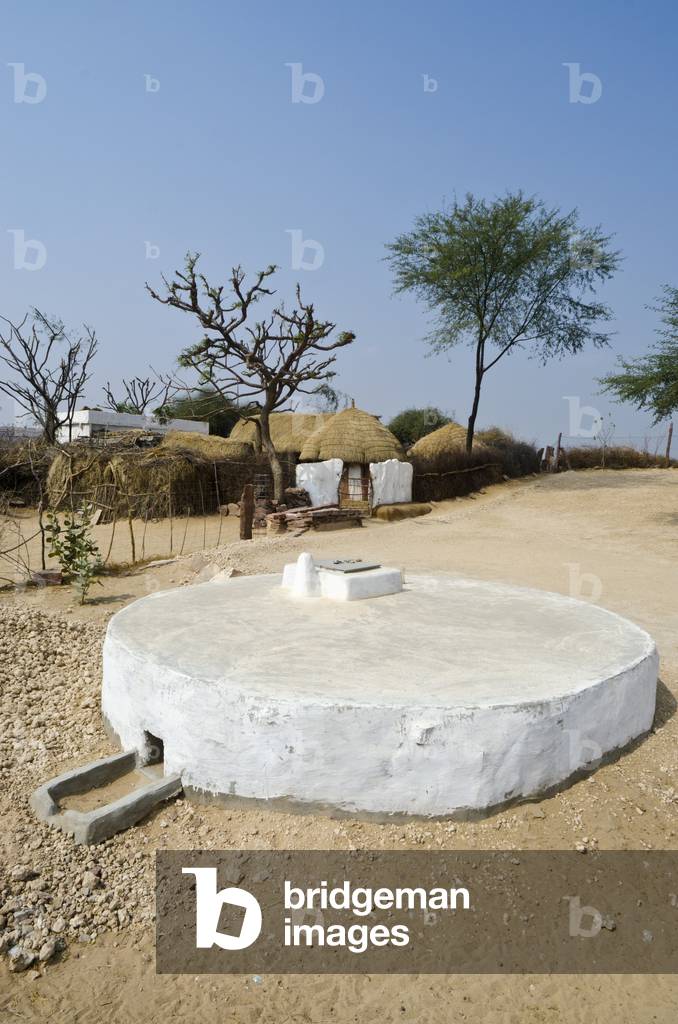 Rainwater harvesting: Underground drinking water storage tank next to thatched huts in desert hamlet,
nr. Jeloo village, Rajasthan, India (photo)