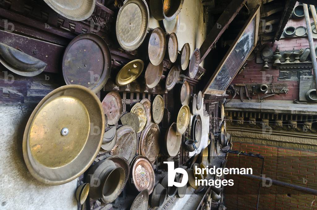 Adinath Lokeshwar Mandir: Kitchen utensils fixed to temple yard walls by newlyweds to ensure happy marriage, carpenter cutting timber for temple repairs, temple dedicated to Red Machhendranath, Chobar, Kathmandu Valley, Nepal (photo)