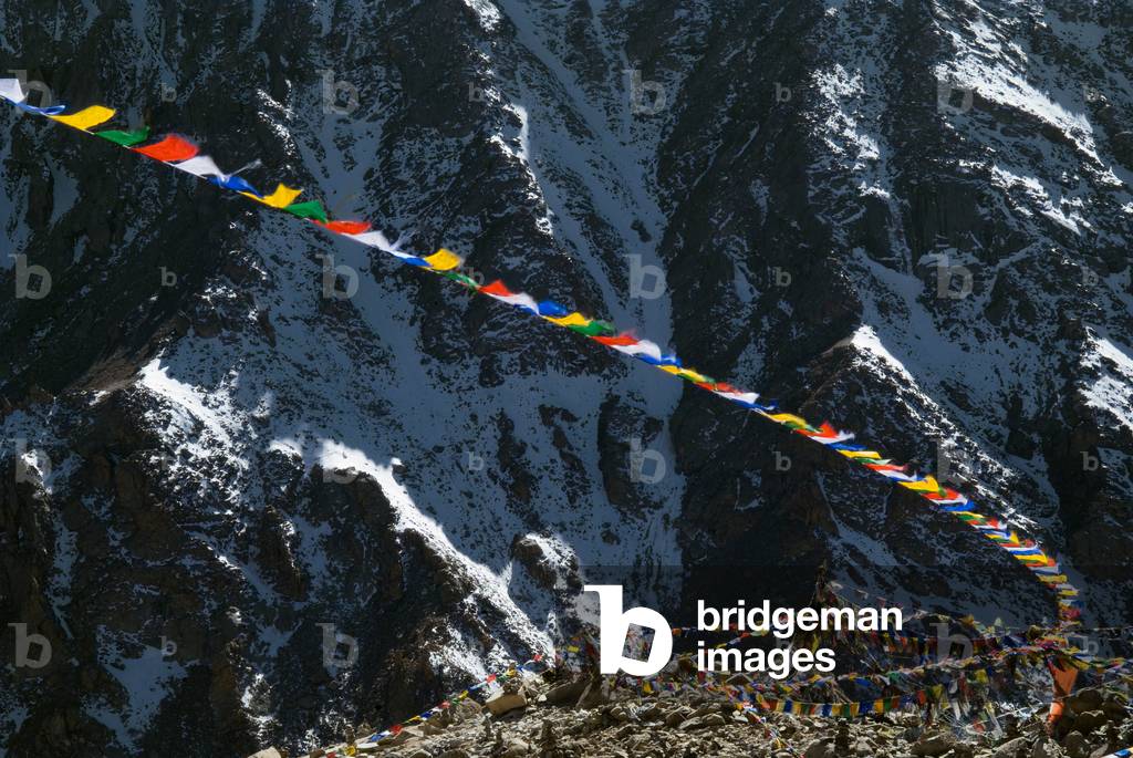 Prayer flags in front of majestic snowy mountainside at top of Khardung la pass (5,606m) north of Leh, Ladakh, Jammu & Kashmir, India (photo)