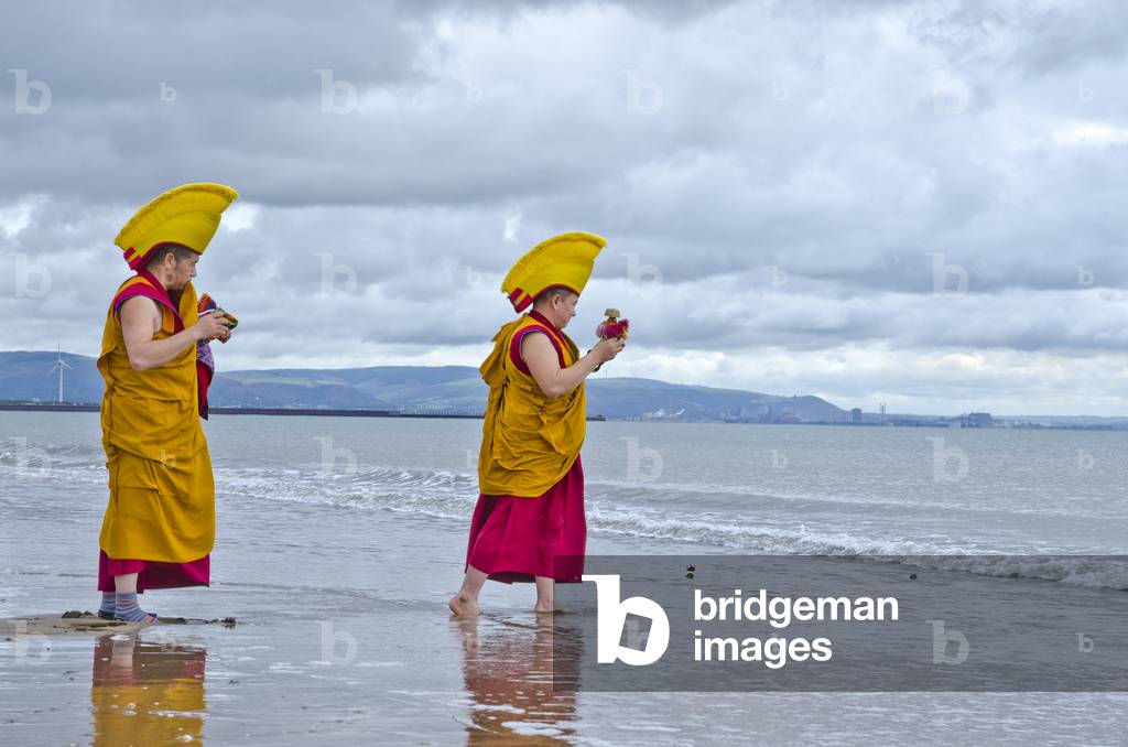 Tibetan Buddhist monks in ceremonial dress on Swansea beach, ending a 5-day sand mandala ceremony during a fundrasing visit to the UK, releasing sand of the completed and swept up mandala into the sea, Swansea, South Wales (photo)