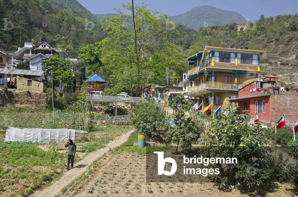 Vegetable beds and fruit trees on Biodynamic Farm, line of international flags, Ankuran Waldorf Inspired School/Nursery building, 
Kahare, Chalnakhel, Kathmandu Valley, Nepal (photo)